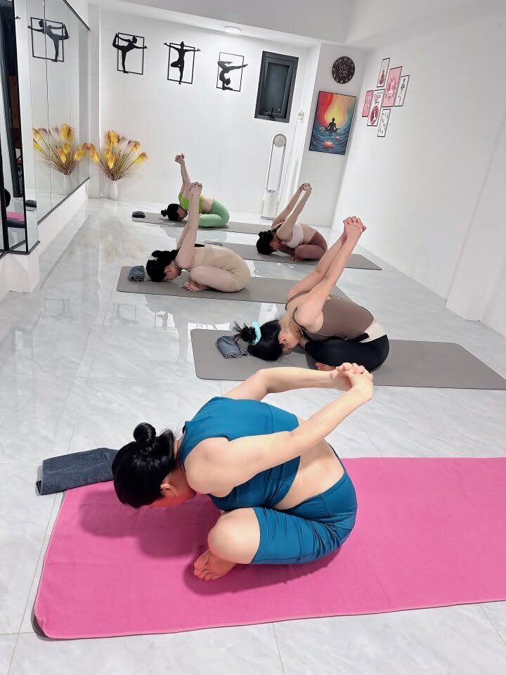 Lớp yoga nhóm gập người về trước khi ngồi, chuẩn bị cơ thể cho thiền tại Yoga Phương Ruby