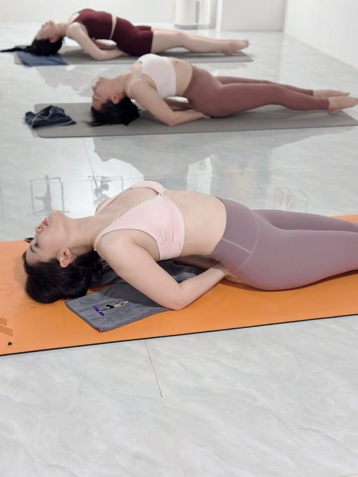 Học viên nằm thư giãn ngả lưng trên khăn kê đỡ – phần tĩnh lặng khi tập Hatha và Vinyasa tại Yoga Phương Ruby Cần Thơ