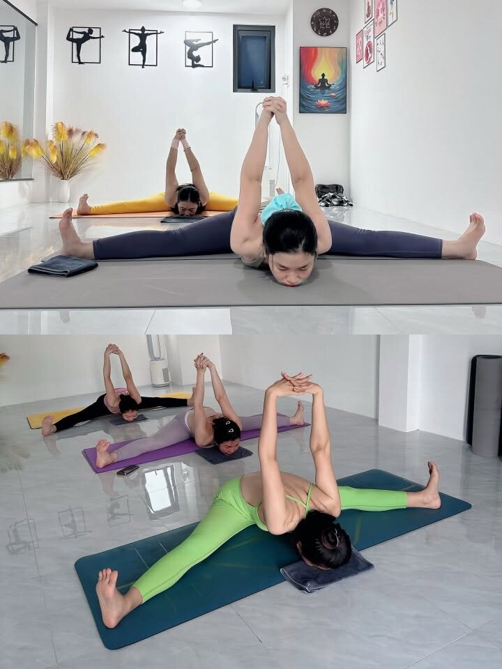 Học viên ngồi dang rộng chân gập người về trước với gối tập hỗ trợ