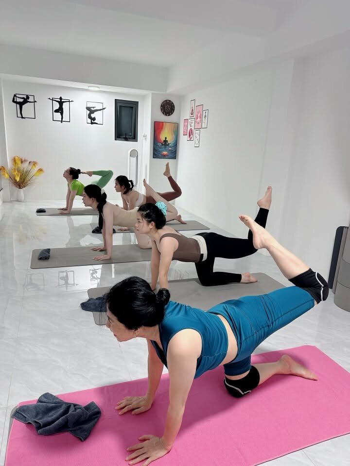 Học viên lớp yoga Cần Thơ tập tư thế nâng chân trên thảm hồng
