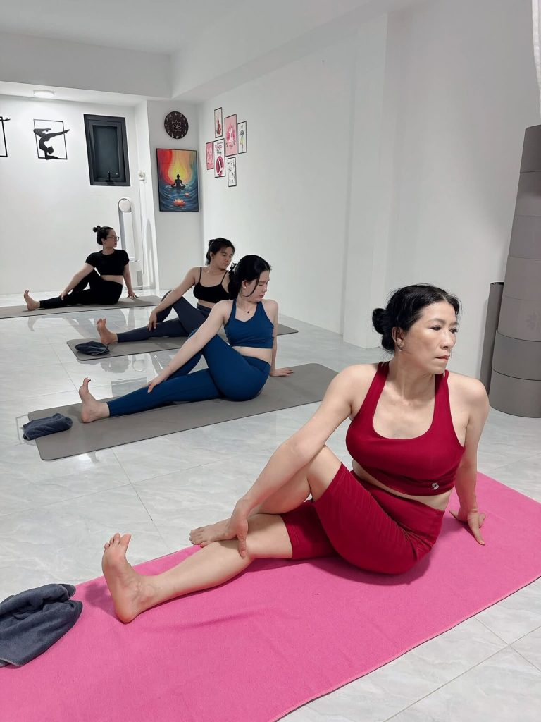 Học viên lớp yoga Cần Thơ ngồi kéo giãn chân trên thảm hồng