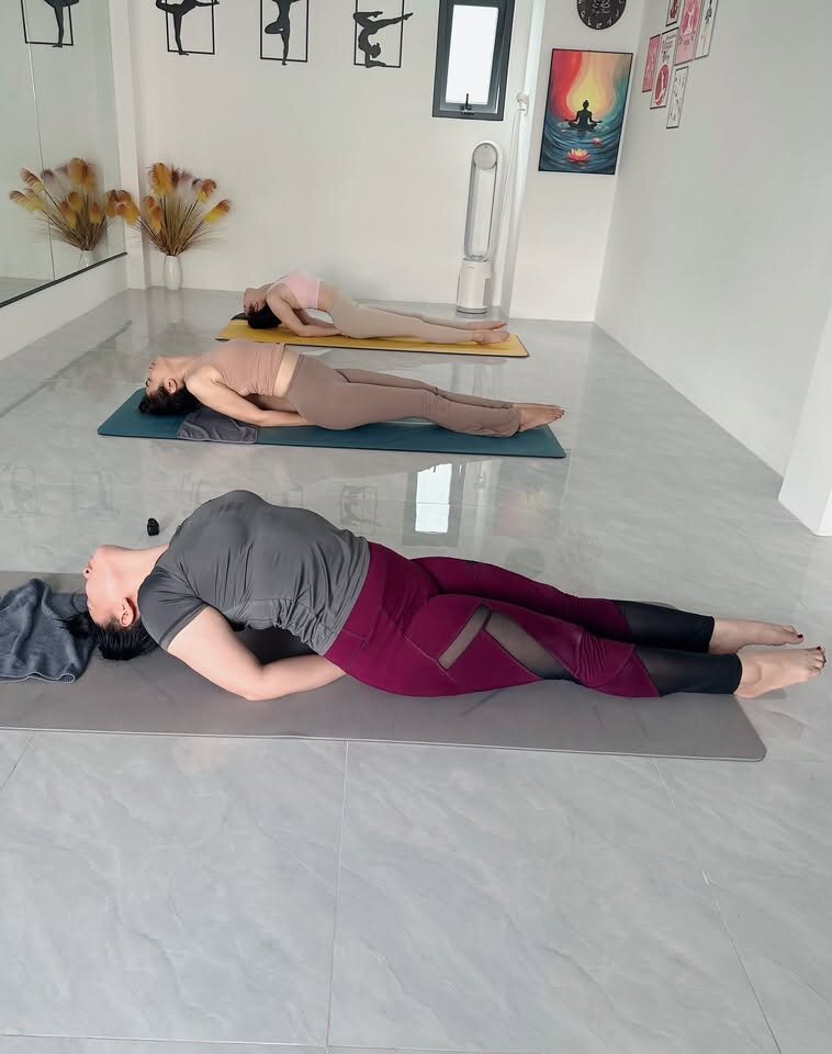 Học viên nằm vặn xoắn cột sống thư giãn cuối buổi yoga trị liệu