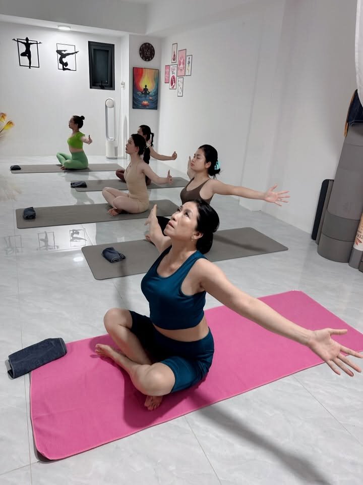 Học viên ngồi dang tay thả lỏng tận hưởng hơi thở sau buổi tập yoga